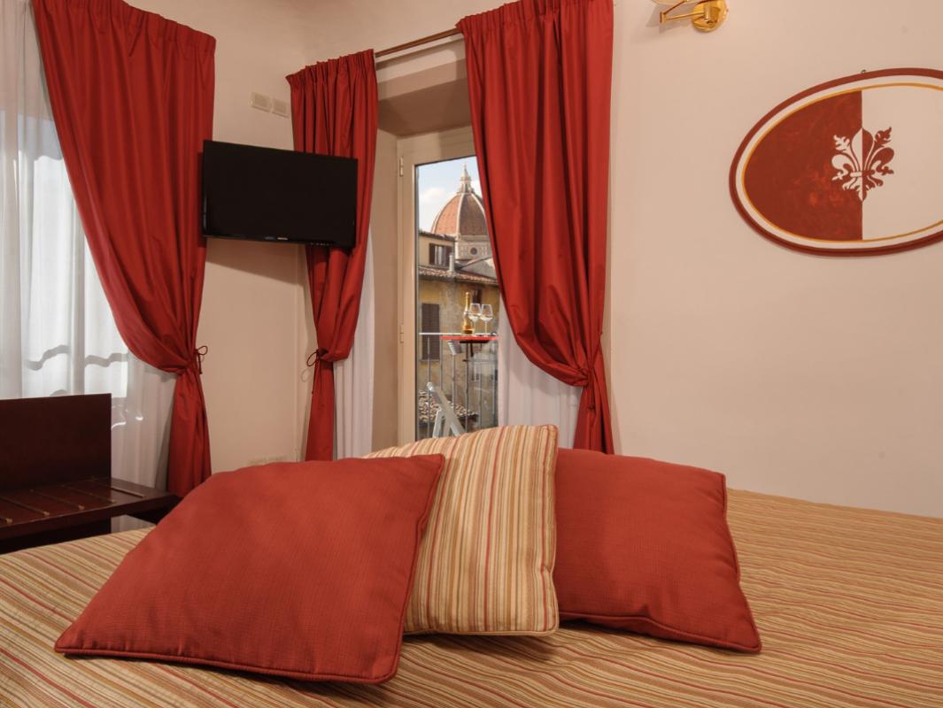 Room with red curtains, TV, view of a historic building.