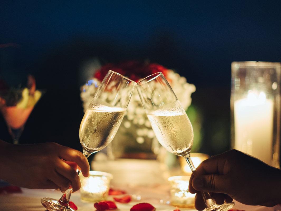 Romantic candlelit toast with rose petals.