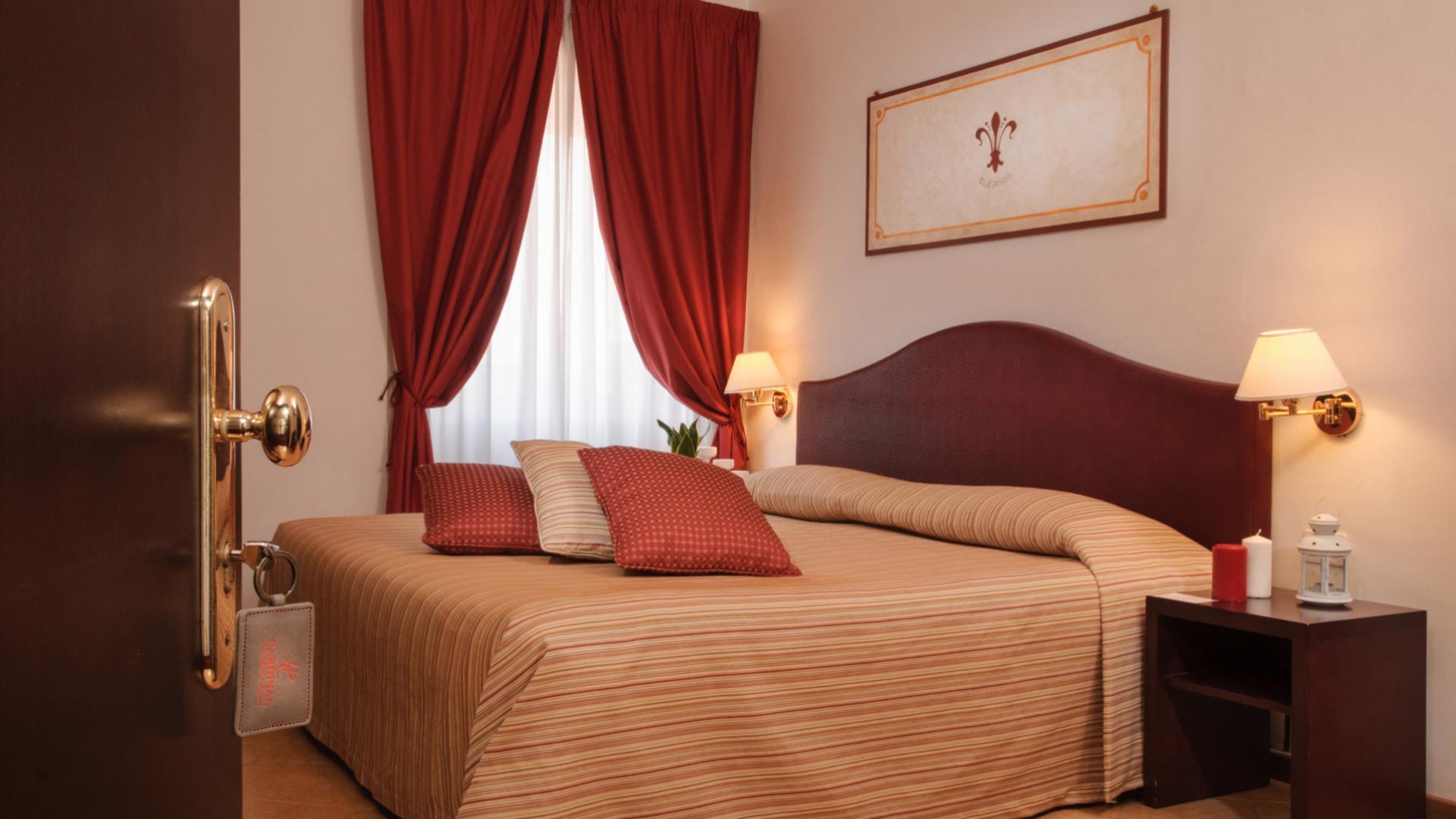 Camera da letto accogliente con letto matrimoniale, cuscini rossi e tenda.