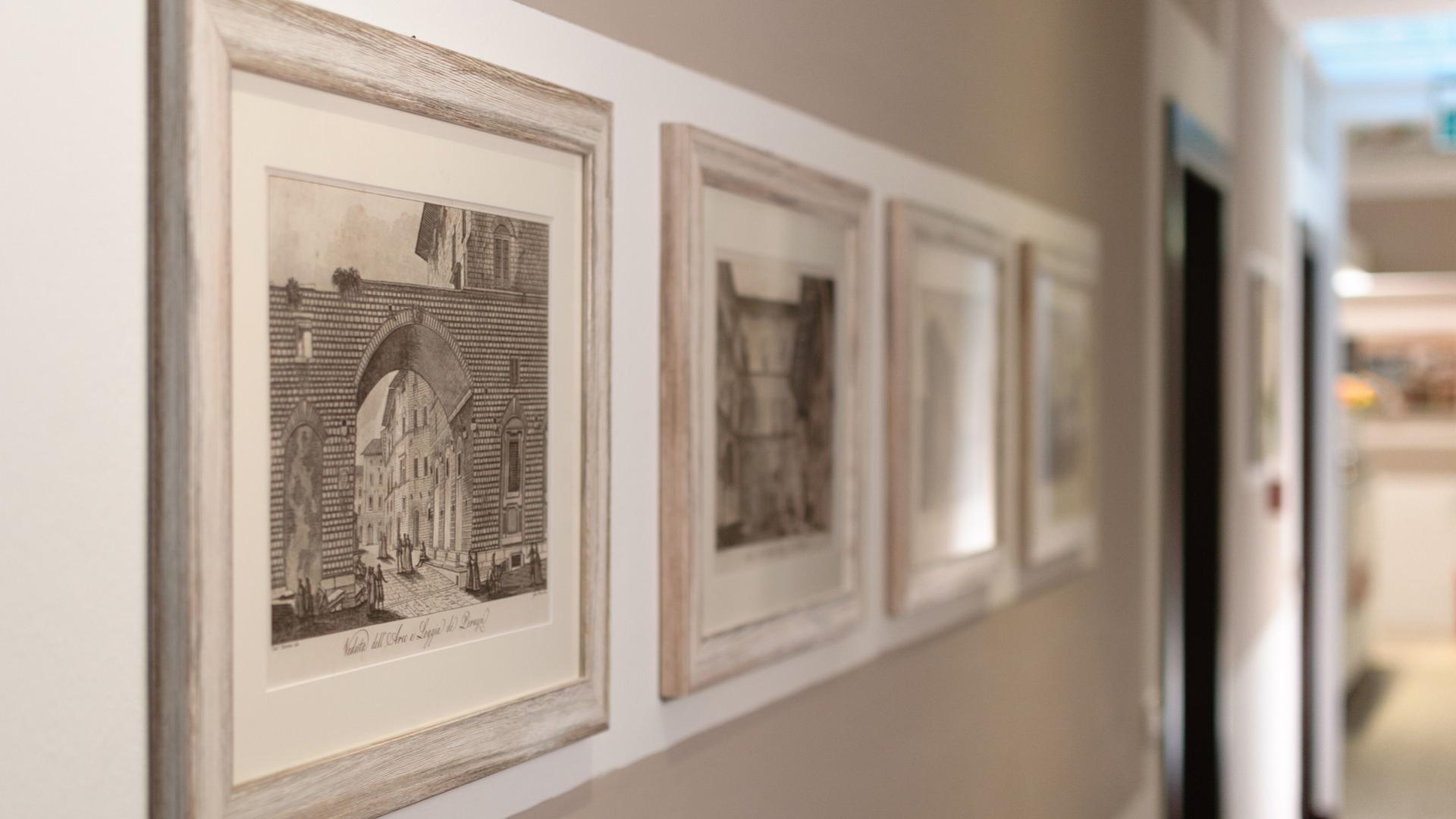 Framed pictures hanging on a wall in a well-lit hallway.