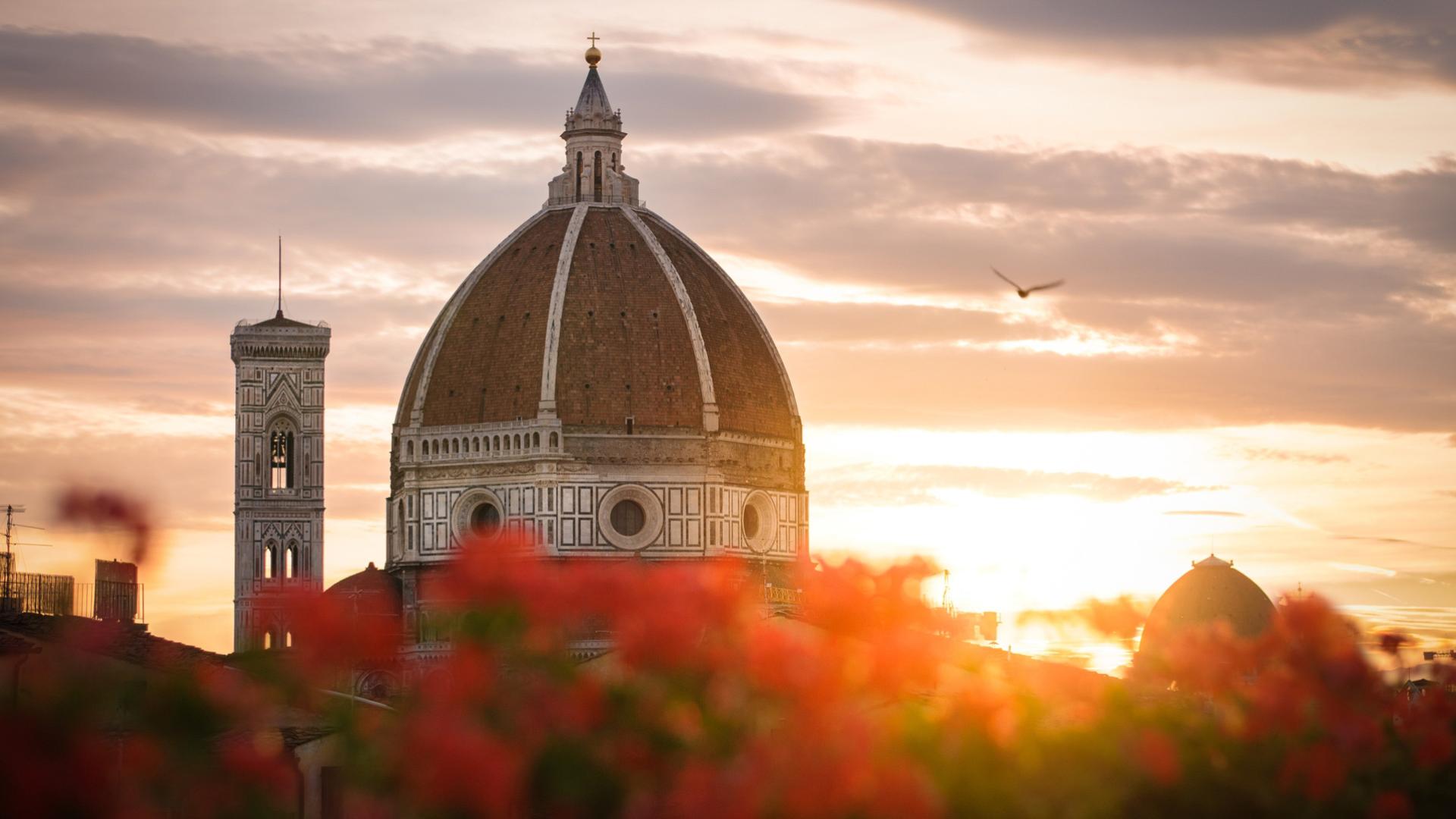 Der Dom von Florenz bei Sonnenuntergang mit Blumen im Vordergrund.