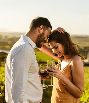 Happy couple toasting in a vineyard at sunset.