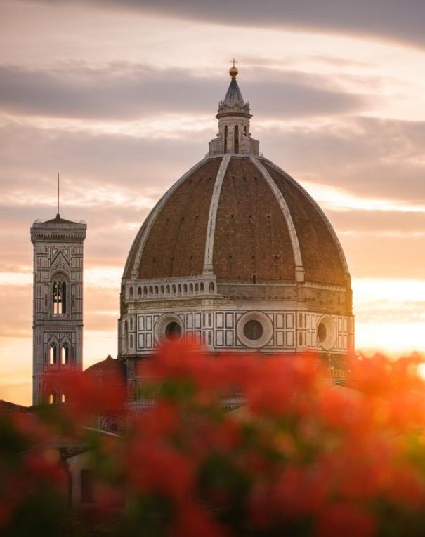 Florence Cathedral dome at sunset, viewed with red flowers.
